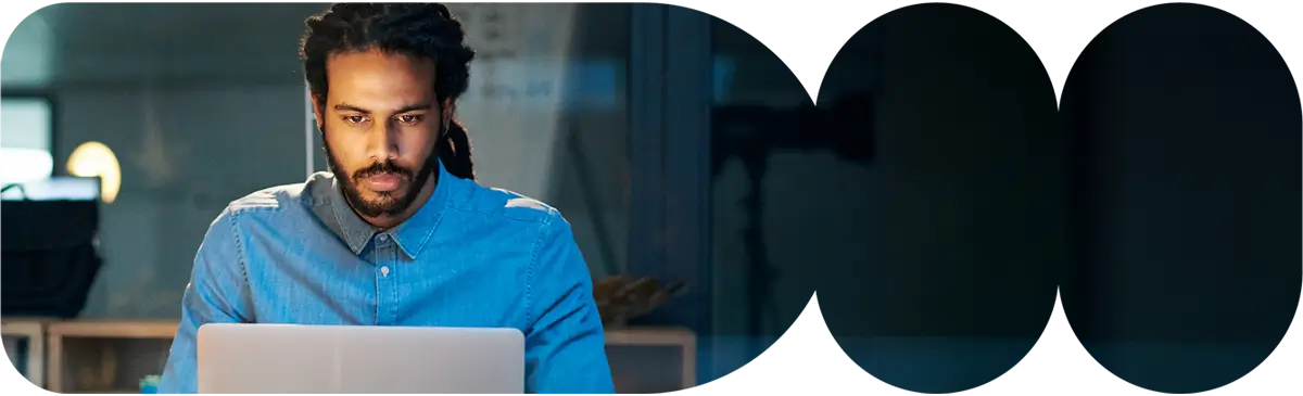 Business professional working on a laptop at a modern desk, focused on digital tasks in a clean office environment.