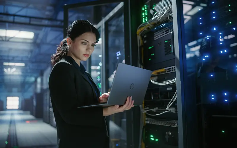 Person looking at a laptop in a data center.