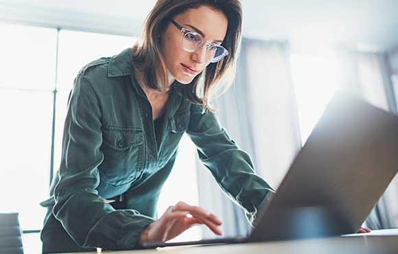 Lady wearing glasses while working on a laptop
