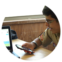 Boy scout checking information on his cell phone, while also using his laptop computer