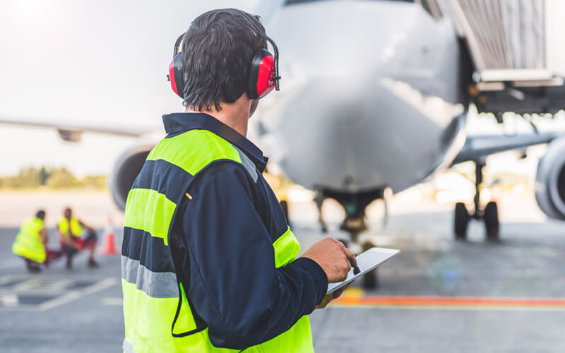 Aircraft engineer uses tablet in front of airplane
