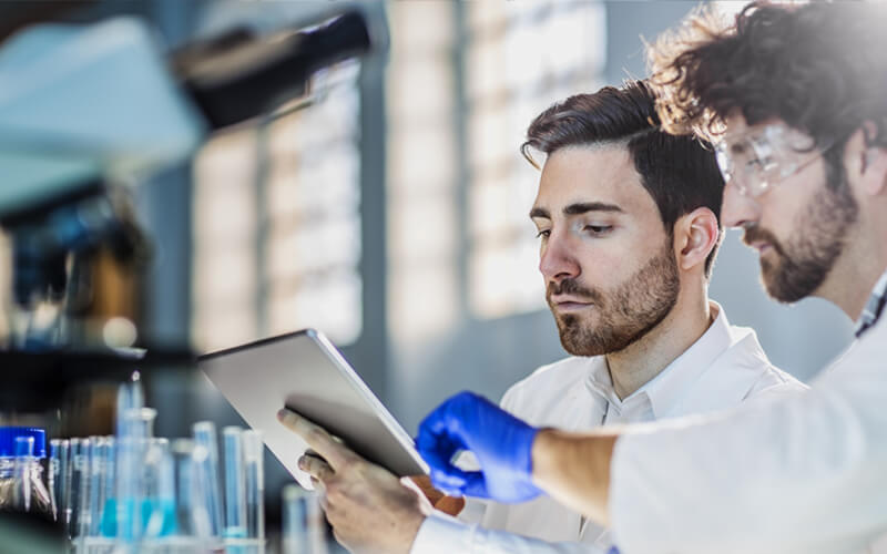 Deux scientifiques travaillant dans un laboratoire avec un microscope et une tablette.