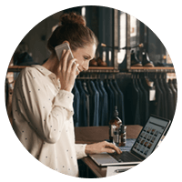 Small business owner on phone and laptop in clothing store