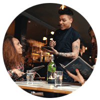 Young woman with a friend placing order to waiter holding digital tablet computer.