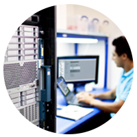 IT technician sitting at a desk in a server room.