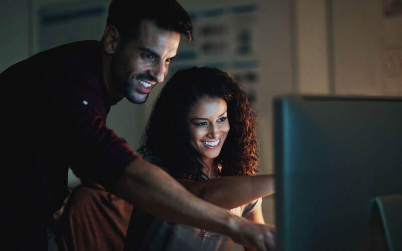 Man and woman smiling at monitor screen