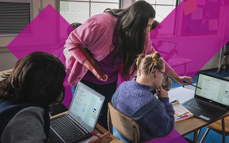 Teacher assisting student on laptop