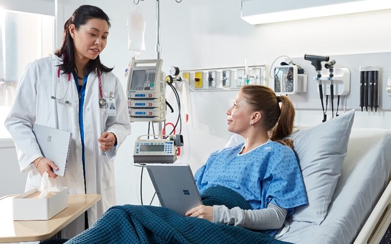 Doctor talking to the patient holding the Microsoft Surface tablet