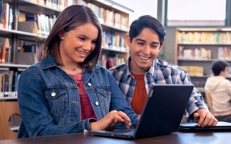 Two students using laptop on library