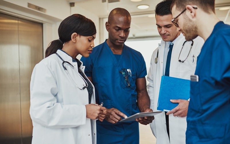 a group of health professional discussing something and using an apple device