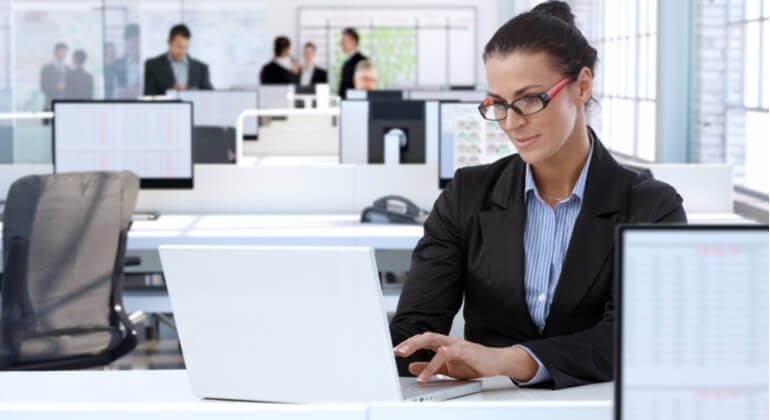 Businesswoman working at office desk, using laptop computer.