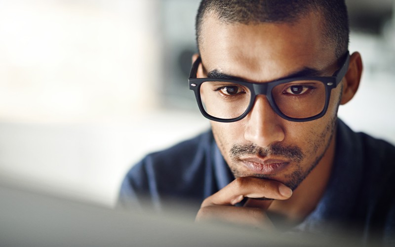 Male with glasses working on desktop device