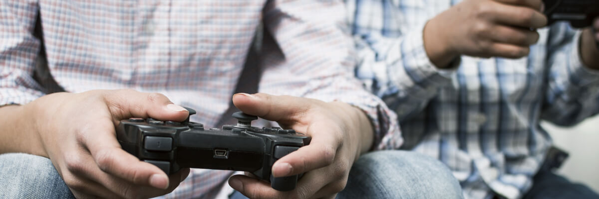 Close up of two people holding gaming console controllers.