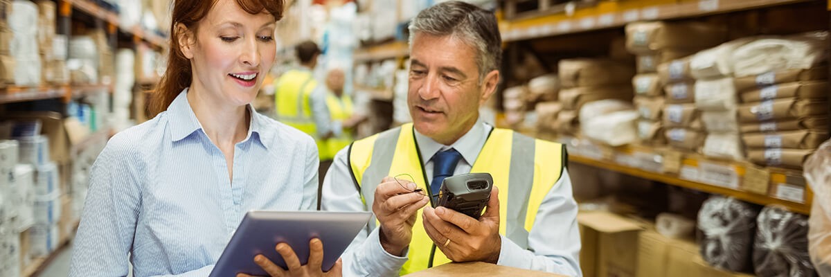 Workers in a warehouse use a POS mobile device.