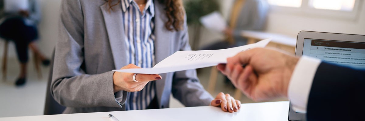 Prospective employee hands resume to recruiter 