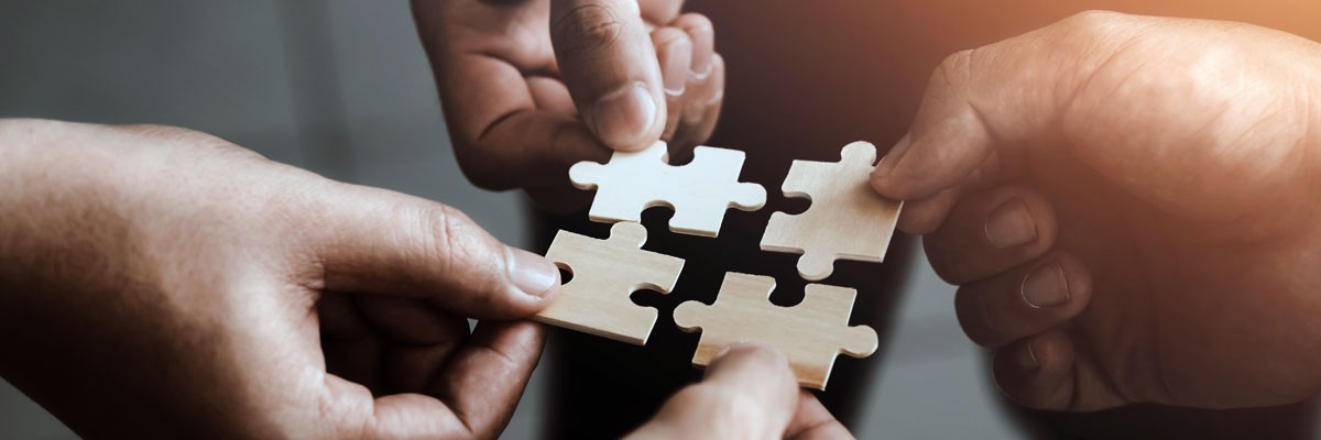 Various teammates holding puzzle pieces that fit together to form a bigger piece