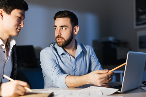 Two IT professionals creating networking strategy in office at night