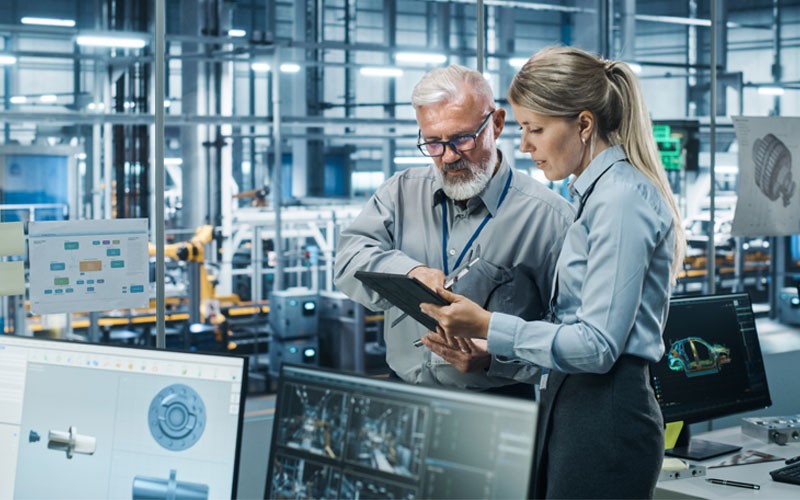 Two engineers in manufacturing facility looking at AI powered insights