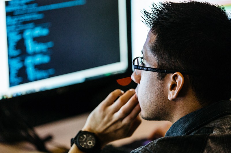 Developer looking at code on desktop computer