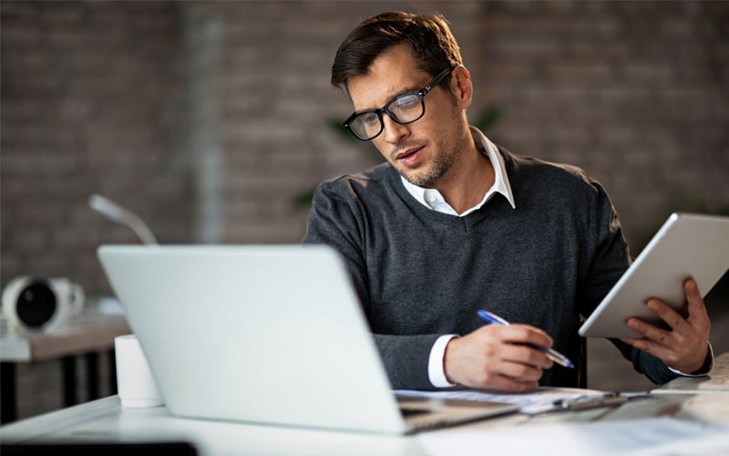 Smiling man reading report on tablet device