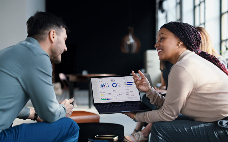 From AI Curious to AI-First: Insight’s Transformation Journey Two Insight colleagues collaborating on AI transformation data and project metrics displayed on a dashboard monitor.