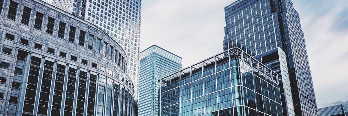 Doctor holding tablet device with patient data while sitting at desk with laptop computer