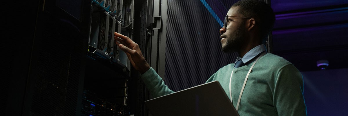 Businessman on laptop device in server room