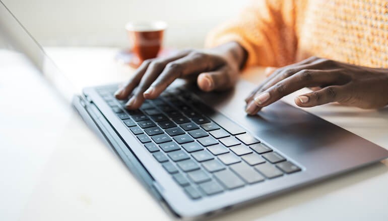 Hands typing on a laptop