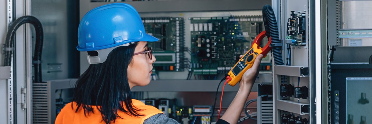 Woman in hard hat tests electronic devices in networking room