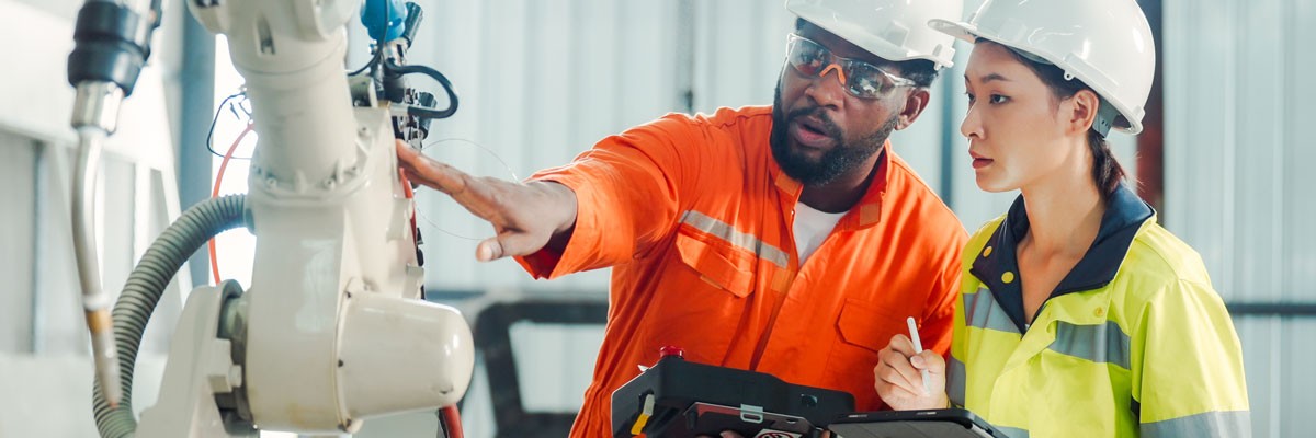Two workers in hard hats on site at a manufacturing facility