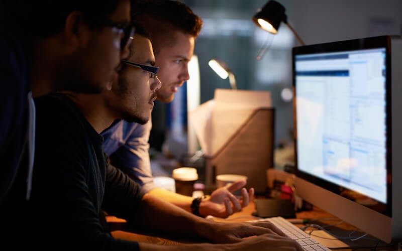 It professionals gather around computer reading cybersecurity report