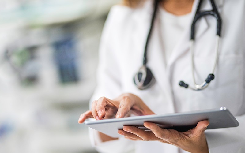Doctor using tablet device to review patient data
