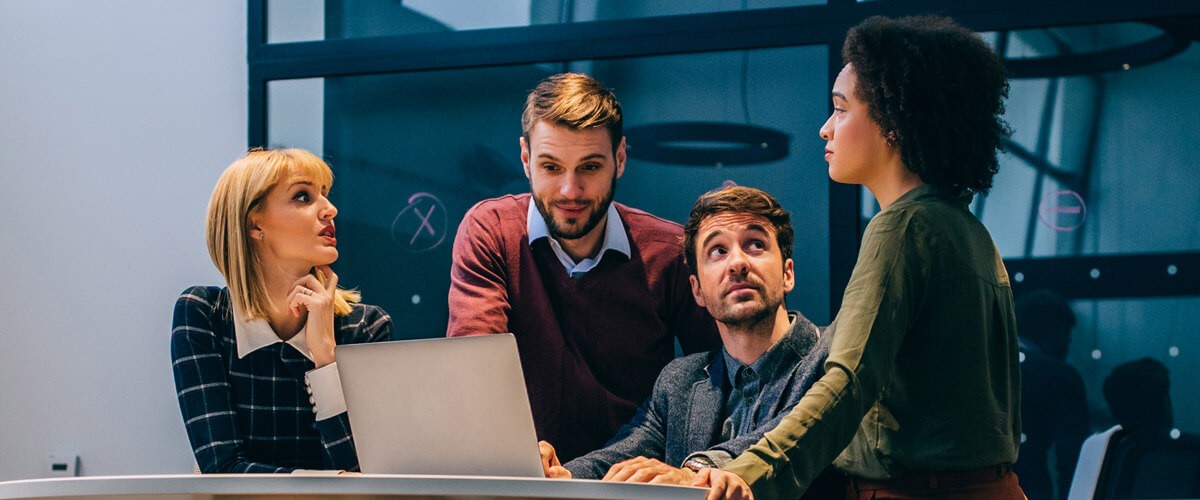  Business team collaborates around computer to have project discussion. Workstream collaboration tools.