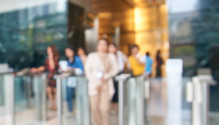 Blurred image of people coming through gates from afar. Return to work Artificial Intelligence for safety, IoT for safety, How to return to work safely 