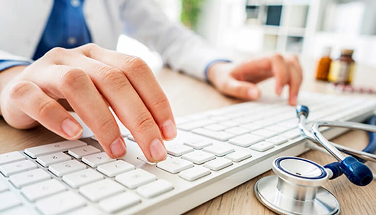 Healthcare professional typing on keyboard