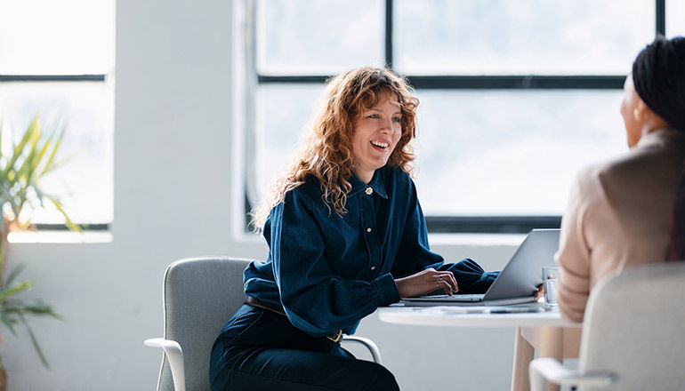 Woman smiling on laptop in meeting