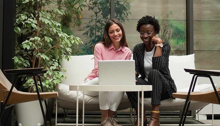 Women working in office on laptop collaborating