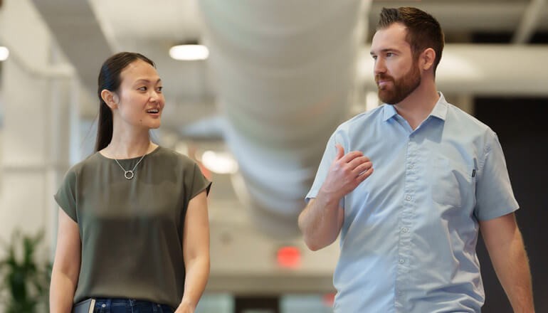 Mentor walking and talking in modern office with mentee