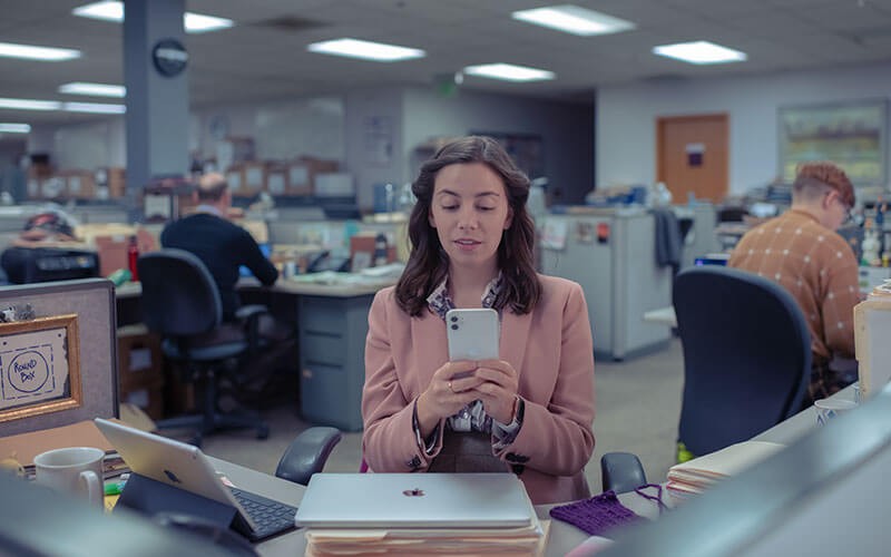 Woman using Apple iPhone and Mac in office