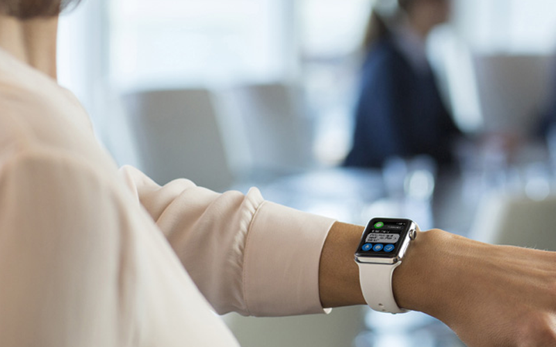 Woman in meeting room holding wrist up to look at her Apple Watch
