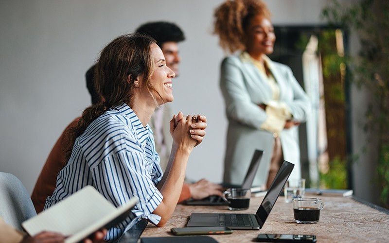 Evolve your digital network with software solutions that drive your business outcome Young woman at desk with laptop reclining in her chair.