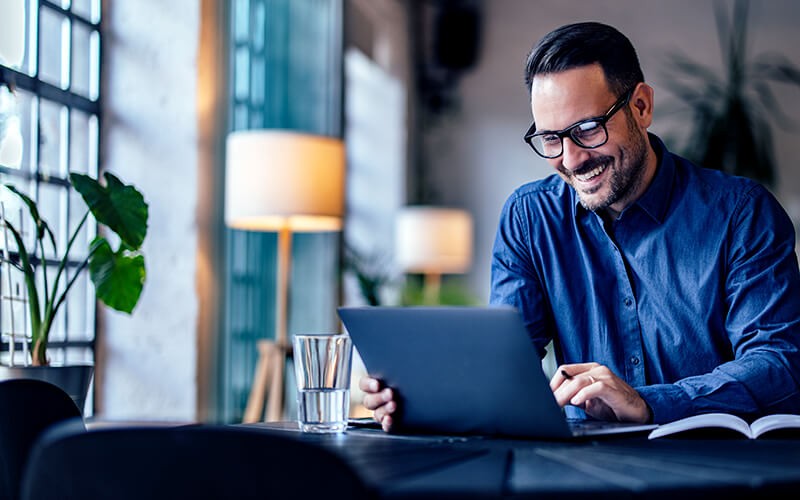 Man smiling using his tablet at the cafe