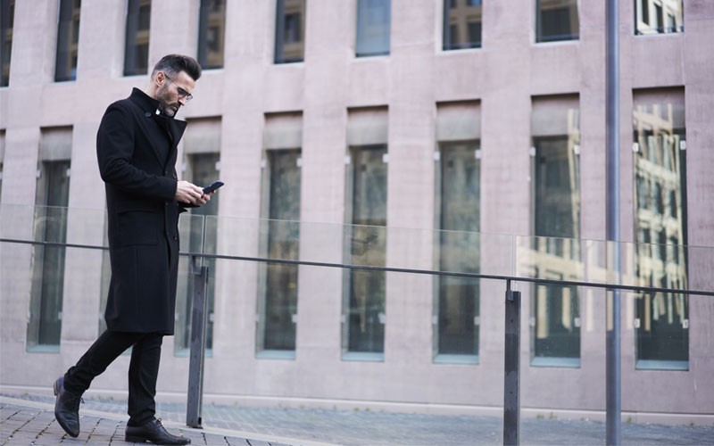 Business man walking outside using cell phone