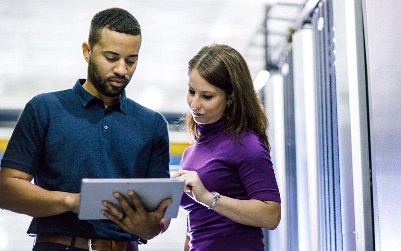 IT admin with business professional touching tablet in data center