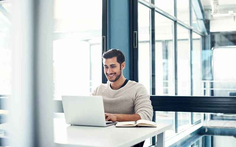 Smiling man on laptop in modern open office