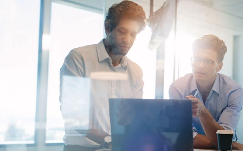 Two men collaborating over laptop