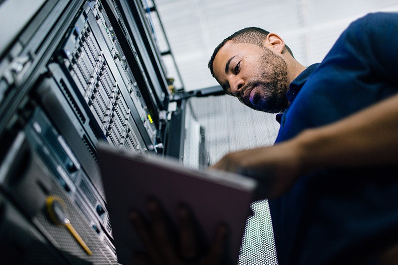 IT admin near server rack on tablet computer