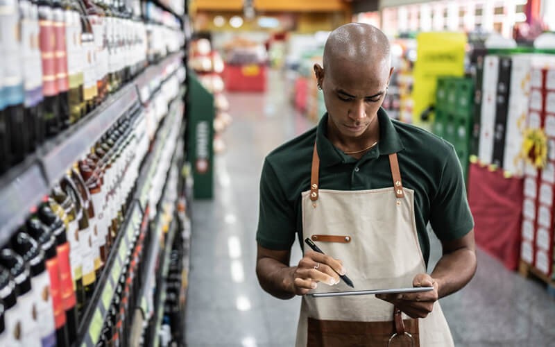 Grocery Clerk on digital tablet in modern supermarket 