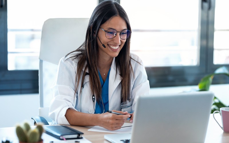 Doctor with headset giving a telehealth consultation on laptop device