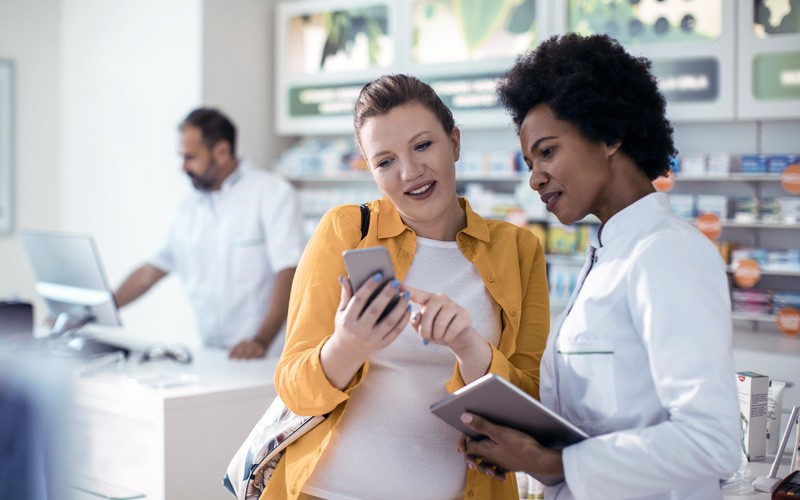 Patient with cell phone asking doctor with tablet a question